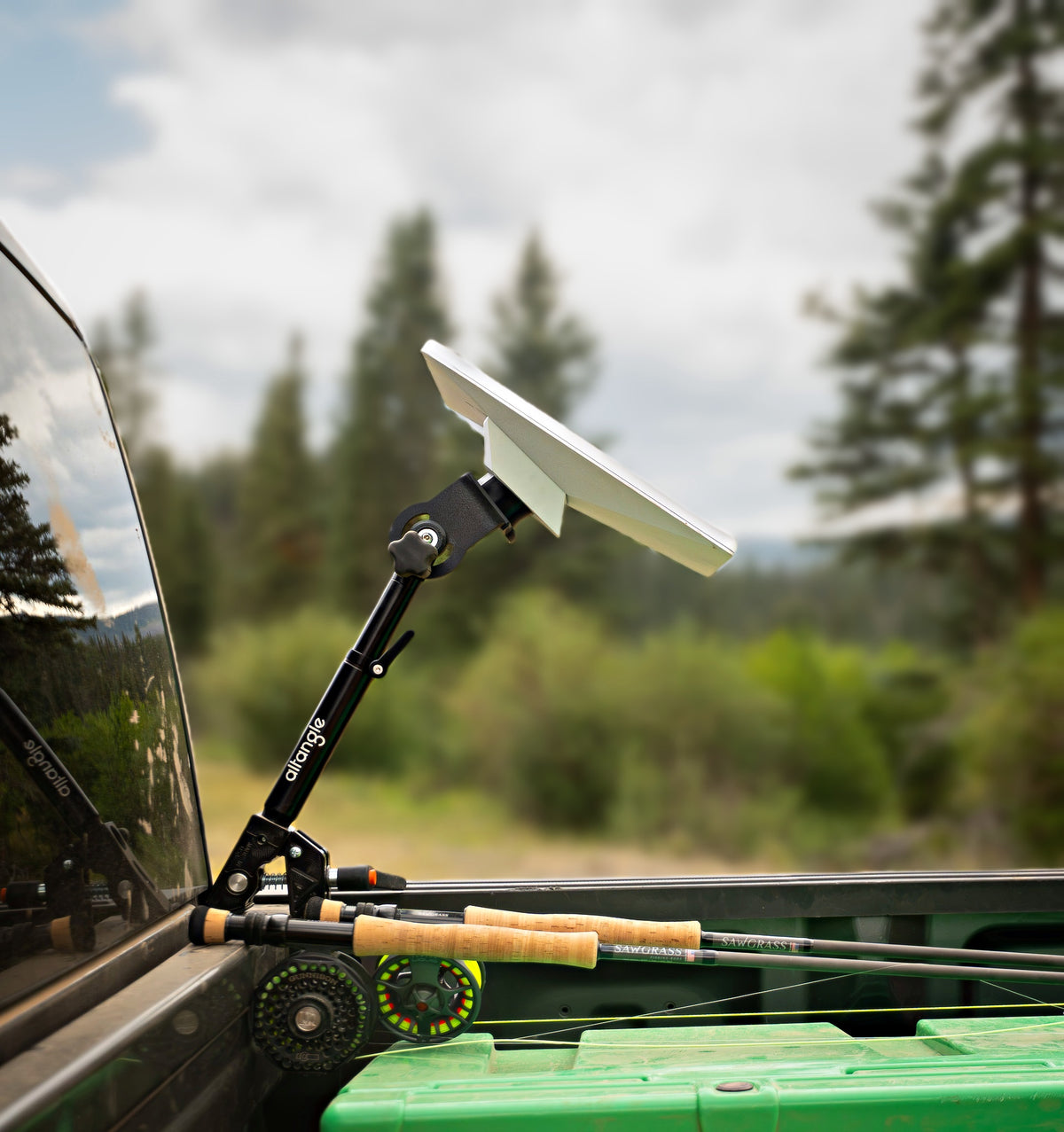 Starlink Mini raised on an Altangle Connect arm clamped to a pickup bed rail, fly rods stowed in the truck bed and pine forest behind