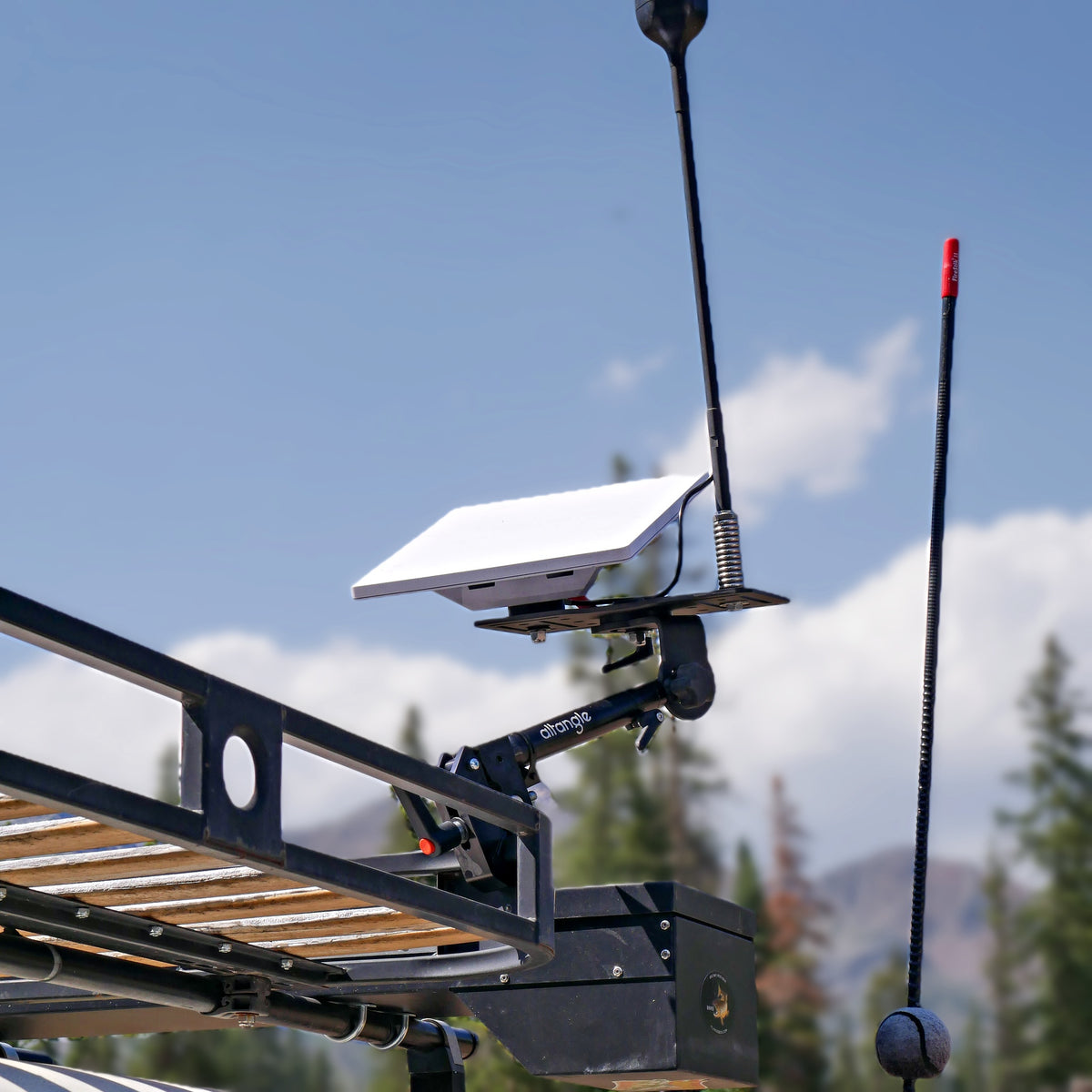 Starlink Mini raised on an Altangle Connect arm mounted to a vehicle roof rack, radio antennas alongside and mountains behind