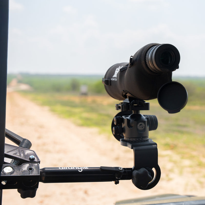 Hub clamped to a truck bed rail with a hunting rifle in an Arca plate, predawn light