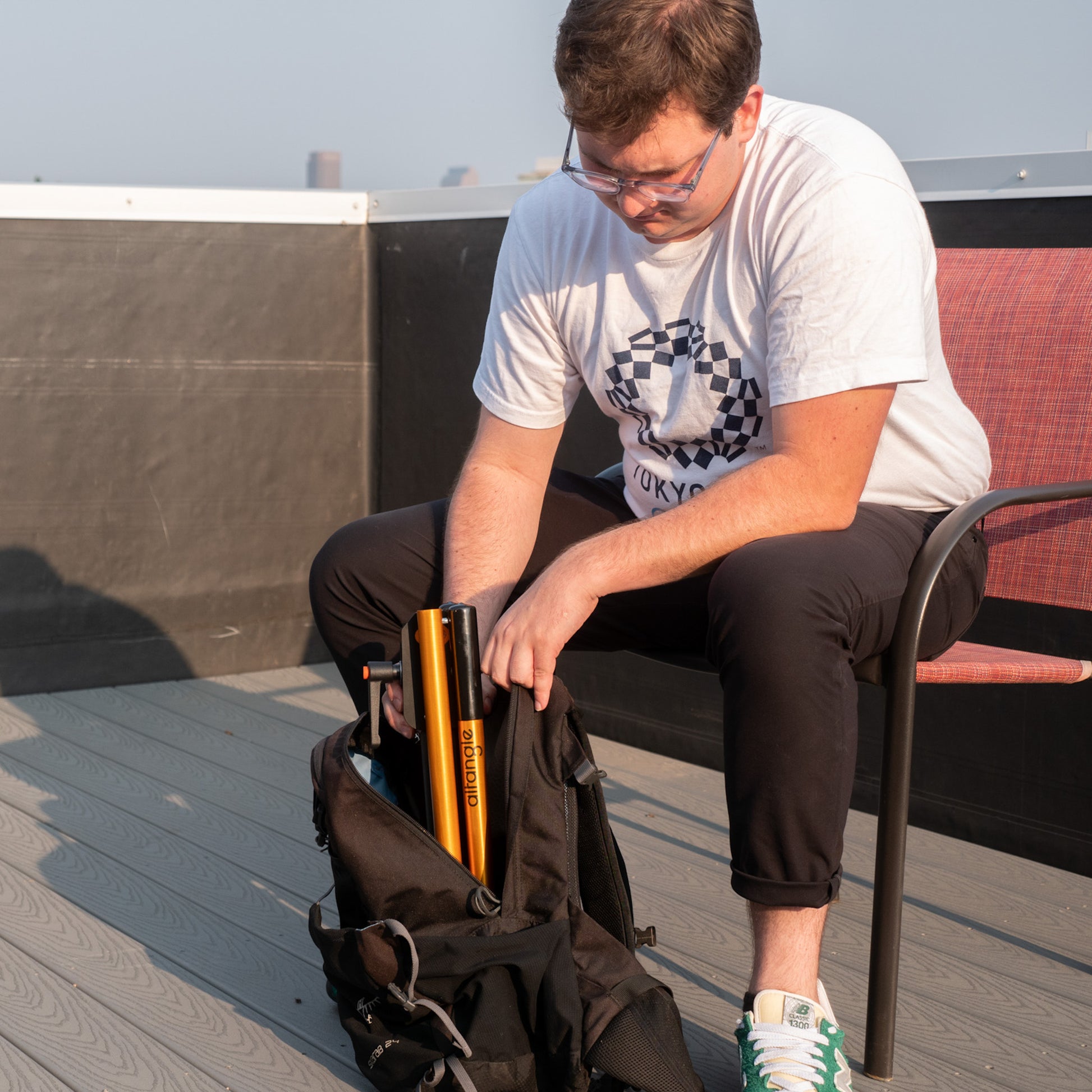 Man removing small collapsable bike repair stand from backpack